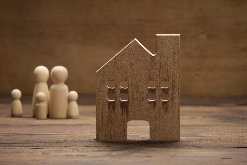 A wooden house and family figurines in the concept of reasons for moving to Wembley.